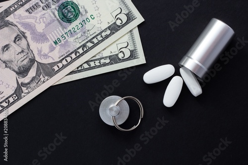 Metal container for pills and money on a black background, concept of expensive drugs, close-up