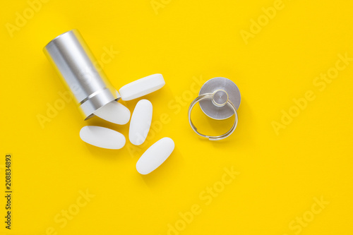 Metal container and pills on a yellow background, close-up photo