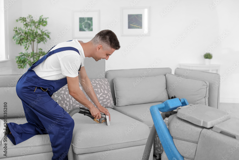 Dry cleaning worker removing dirt from sofa indoors Dry cleaning worker removing dirt from sofa indoors