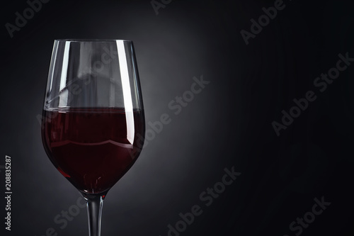 Glass with delicious red wine on dark background