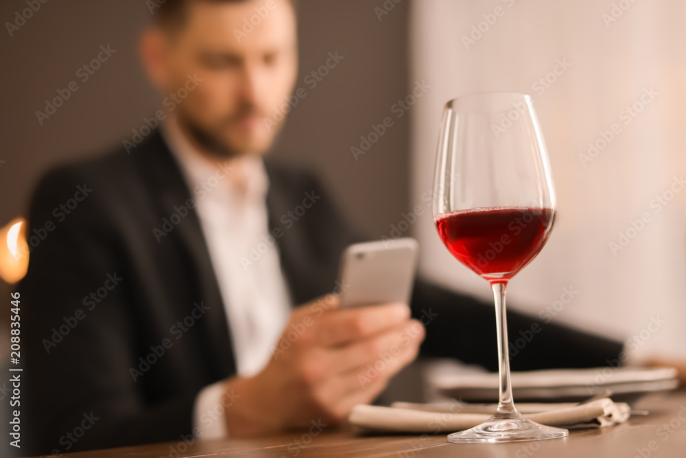 Glass of delicious wine and blurred man on background