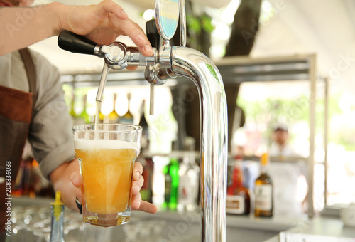 Bartender pouring fresh cold beer from tap, closeup