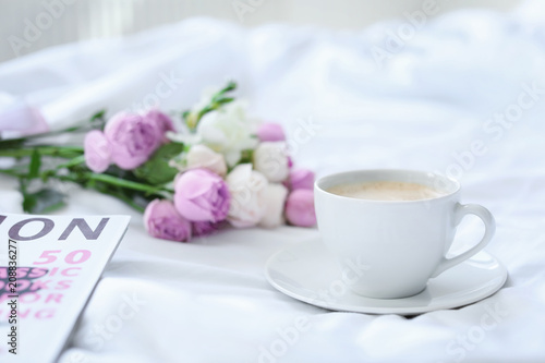 Cup of coffee, beautiful flowers and magazine on fabric