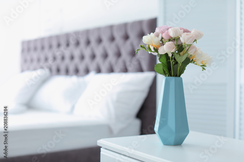 Vase with beautiful flowers on table in bedroom