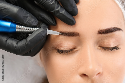 Young woman undergoing eyebrow correction procedure in salon, top view photo