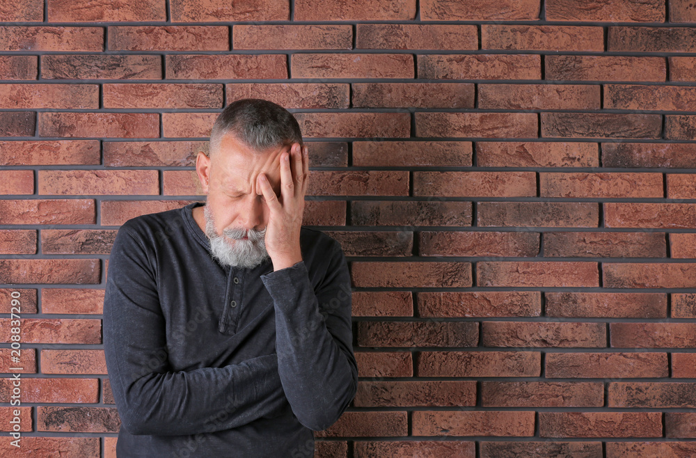 Senior man in state of depression near brick wall Senior man in state of depression near brick wall