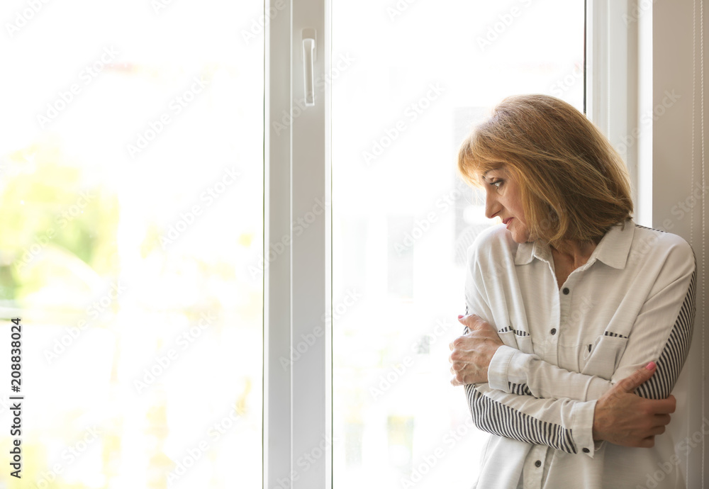 Senior woman suffering from depression near window Senior woman suffering from depression near window