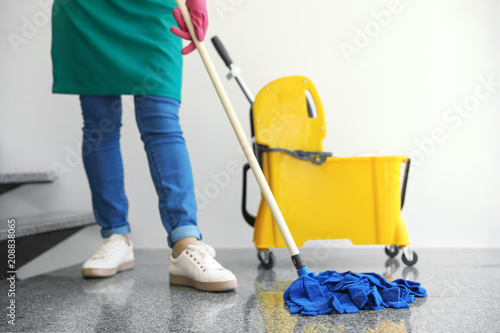 Young woman with mop cleaning stairs