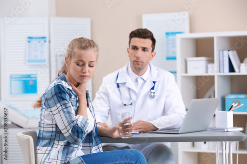 Coughing young woman visiting doctor at clinic