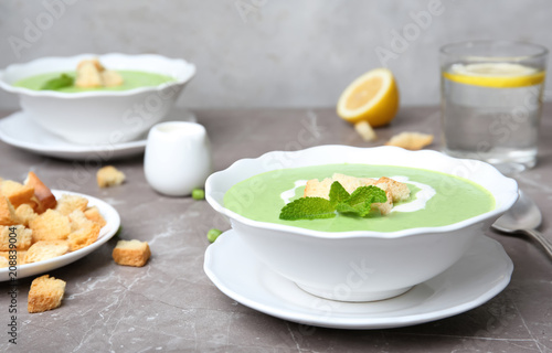 Green pea soup with croutons in bowl on table