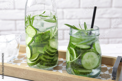 Natural lemonade with cucumber and rosemary in glassware on table