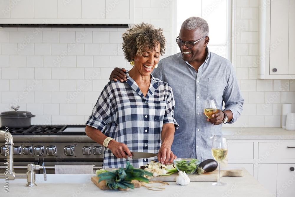 Senior African American couple chopping vegetables together in the kitchen Senior African American couple chopping vegetables together in the kitchen