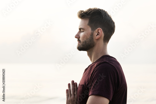 Man practicing yoga on the beach