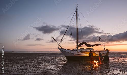 Two friends stay warm during there adventure  after they got stuck with their sailboat on a sandbank when being surprised by low tide photo
