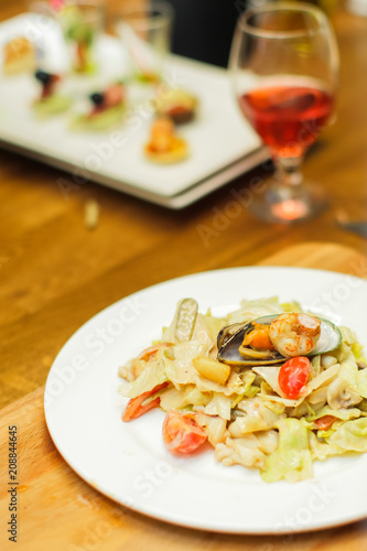 Warm salad with seafood with a glass red wine on a wooden table