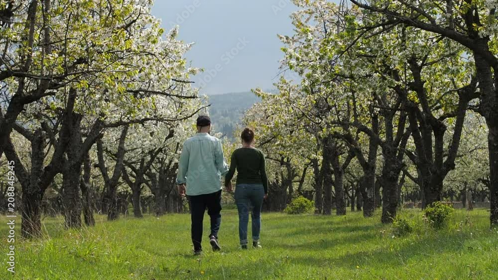 A young couple in love stroll together through a beautiful forest with their pet dog. In slow motion. A young couple in love stroll together through a beautiful forest with their pet dog. In slow motion.