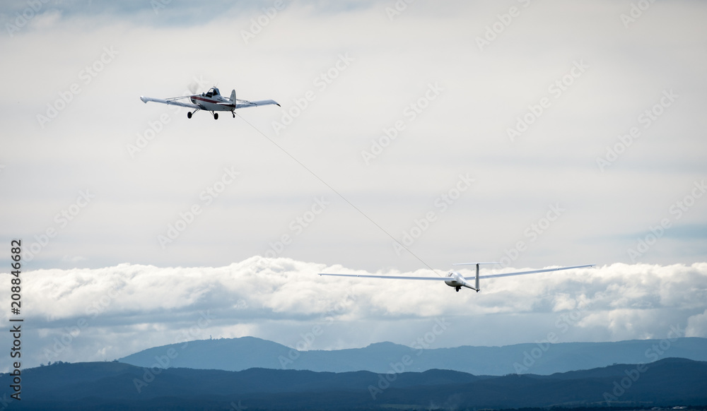 Glider on tow against mountains and cloud Glider on tow against mountains and cloud