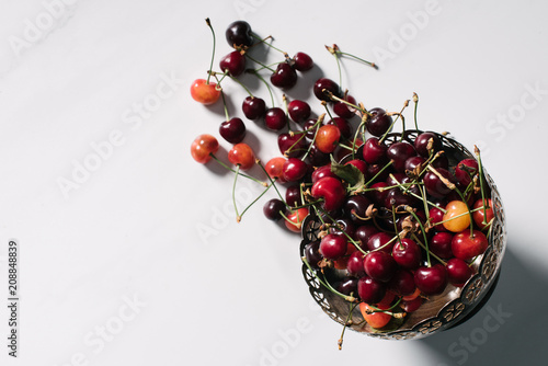 top view of fresh ripe sweet cherries in vintage bowl on white
