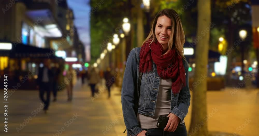 Stylish Caucasian woman on urban street in Paris, Woman in her 20s on the Champs-Elysees at night smiling at camera, 4k Stylish Caucasian woman on urban street in Paris, Woman in her 20s on the Champs-Elysees at night smiling at camera, 4k