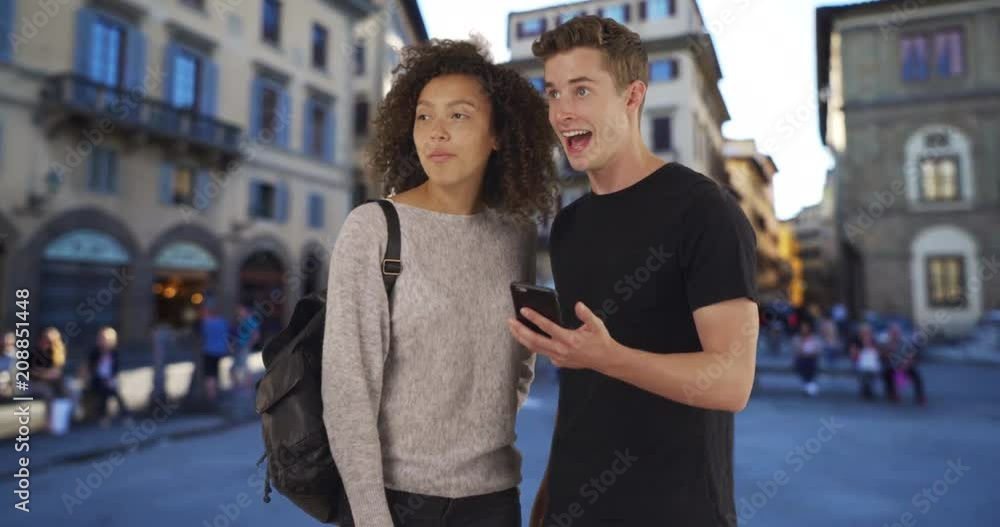 Portrait of two millennial tourists using map on smartphone in Florence, Multiethnic male and female use cellphone for directions on Florence street, 4k Portrait of two millennial tourists using map on smartphone in Florence, Multiethnic male and female use cellphone for directions on Florence street, 4k