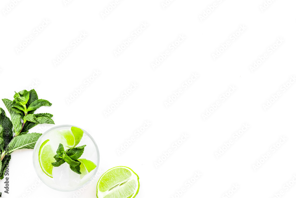 Refreshing mojito cocktail. Slices of lime, mint, glass with ice cubes on white background top view space for text Refreshing mojito cocktail. Slices of lime, mint, glass with ice cubes on white background top view space for text