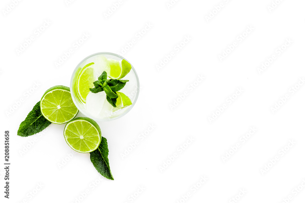 Refreshing mojito cocktail. Slices of lime, mint, glass with ice cubes on white background top view space for text Refreshing mojito cocktail. Slices of lime, mint, glass with ice cubes on white background top view space for text