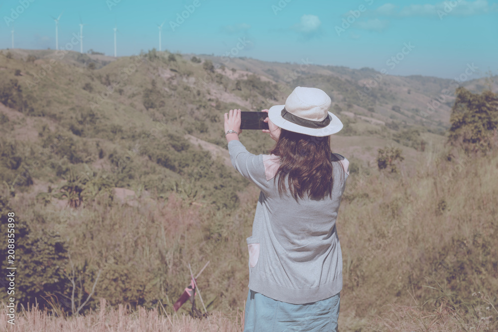 Young asian woman tourist taking photo of mountain view with smart phone