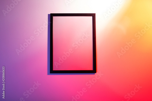 Empty frame hanging on a colorful wall photo