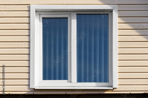 Window of a private house on a background of beige siding.