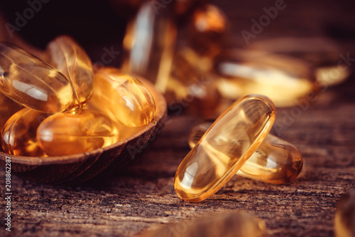 Fotografi Close up the vitamin D and Omega 3 fish oil capsules supplement on wooden plate