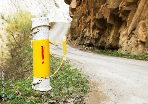 Fencing posts on a steep section of a narrow mountain road with a warning