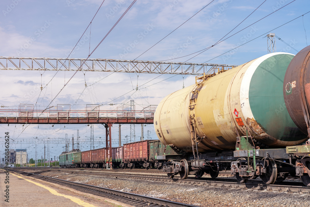 Naklejka premium View of railway station with industrial freight trains on railroad under summer sky with clouds. Russia, May 2018