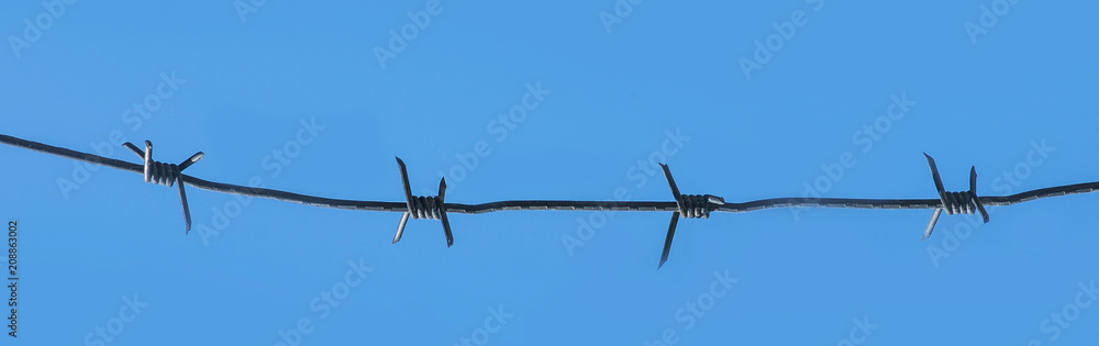 Barbed wire on blue sky background. Panoramic view Barbed wire on blue sky background. Panoramic view