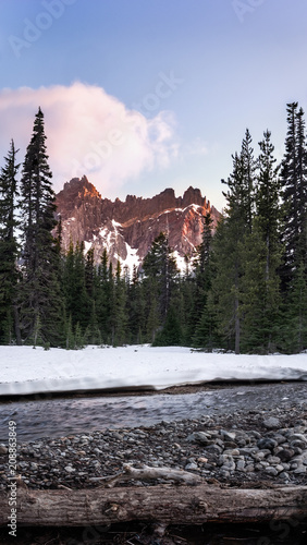 Mountain landscape sunset with forest, snow, and river