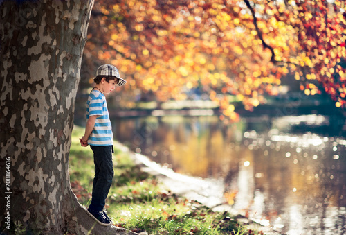 Boy in a park beside a lake in autumn with fall colors photo