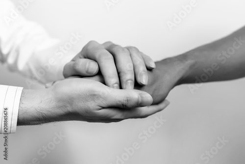 Two people holding hands for comfort. Doctor consoling relatives of patients in hospital concept. black and white.