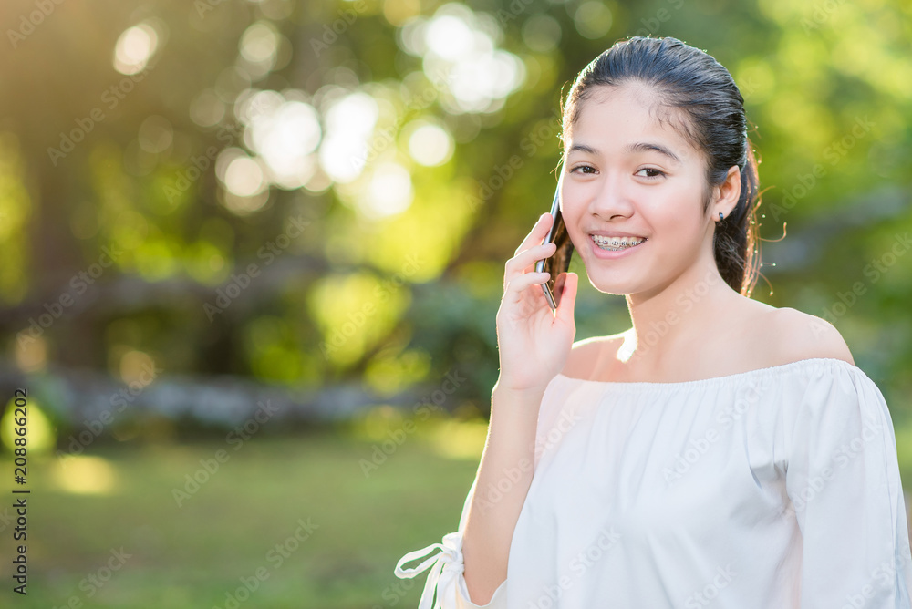 Asian Young happy woman talking on cell phone in summer park. Asian Young happy woman talking on cell phone in summer park.