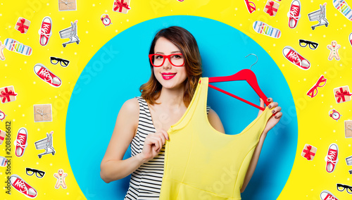 portrait of beautiful young woman with dress on hanger on the wonderful blue studio background and with clothes