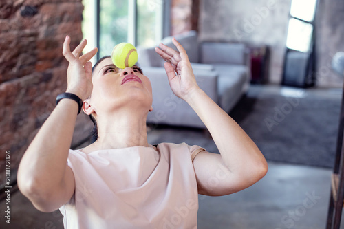 Game at work. Concentrated female employee looking up and playing with ball