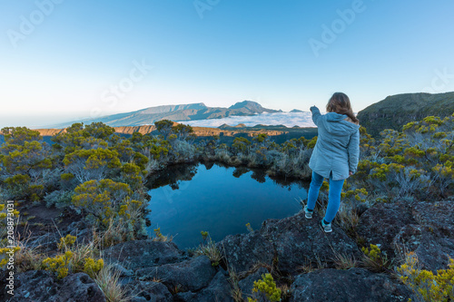 Girl pointing the Piton des Neiges over a lake in Reunion Island