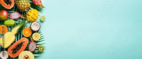 Panel kuchenny z motywem Exotic fruits and tropical palm leaves on pastel turquoise background - papaya, mango, pineapple, banana, carambola, dragon fruit, kiwi, lemon, orange, melon, coconut, lime. Banner. Top view.