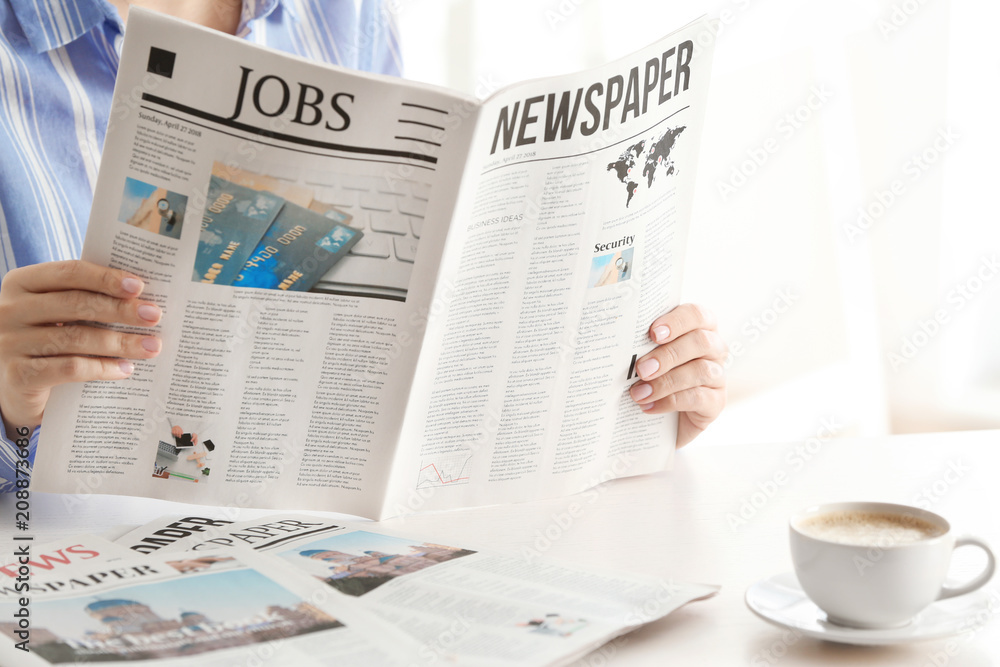 Obraz premium Woman reading morning newspaper indoors