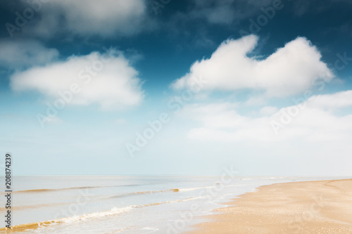 Sandy beach and blue sky with clouds.