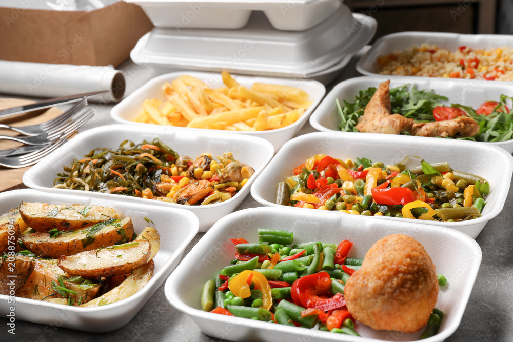 Foam plastic containers with delicious food on table