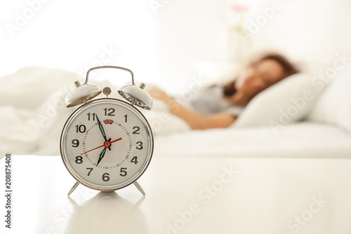 Alarm clock on table in bedroom of beautiful young woman. Morning time