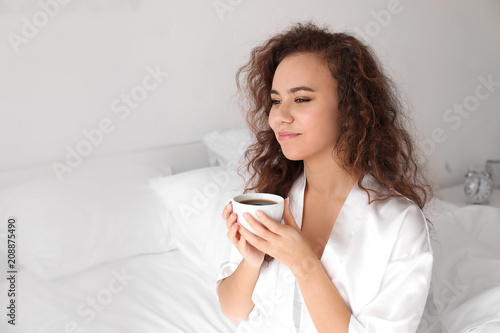 Morning of beautiful African-American woman drinking coffee at home