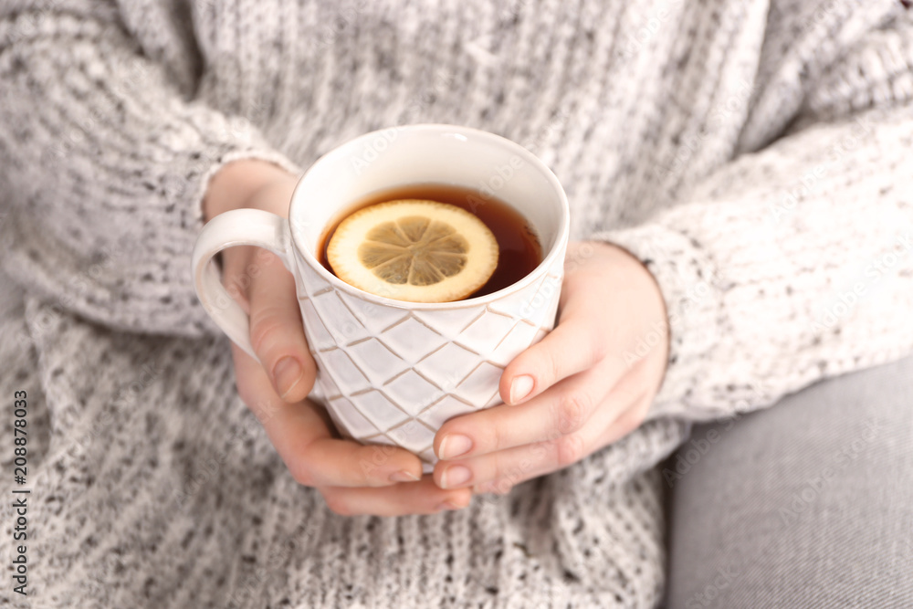 Young woman holding mug of hot aromatic tea with lemon, closeup Young woman holding mug of hot aromatic tea with lemon, closeup