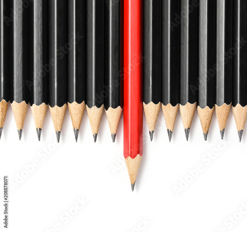 Red pencil standing out from crowd of plenty identical black fellows on white table. Leadership, uniqueness, independence, initiative, strategy, dissent, think different, business success concept