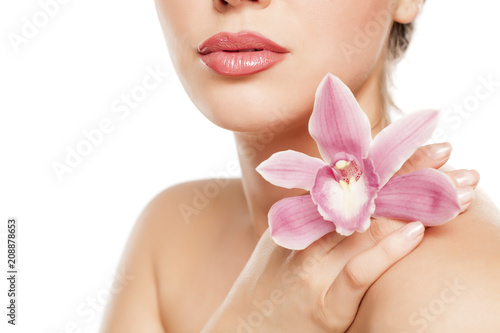 a pretty young woman with orchid on her shoulder on a white background