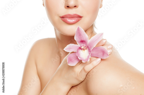 a pretty young woman with orchid on her shoulder on a white background